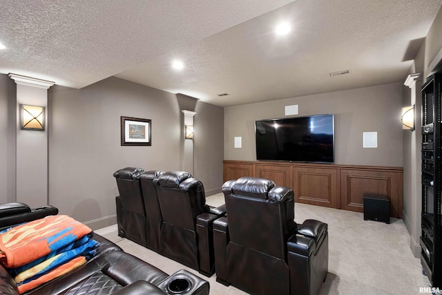 home theater room with light colored carpet and a textured ceiling