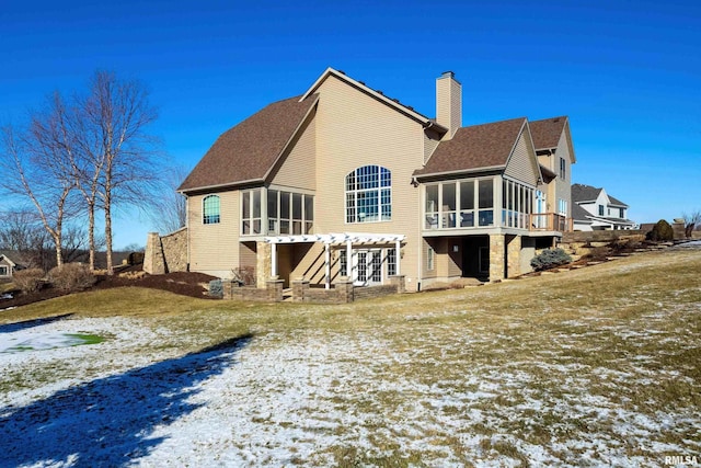 snow covered property featuring a pergola, a lawn, and a sunroom