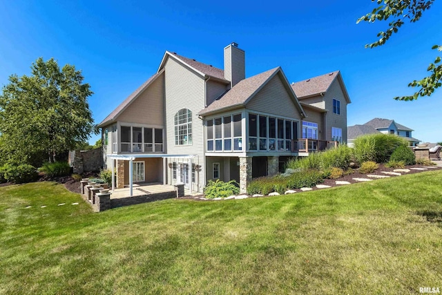 back of property with a lawn, a sunroom, and a patio