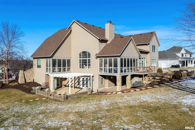 snow covered back of property with a pergola, a patio area, and a sunroom