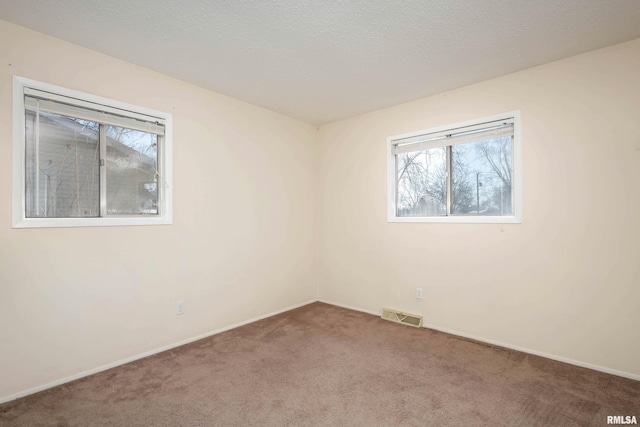 carpeted empty room featuring a textured ceiling