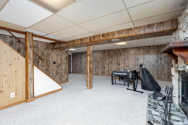 basement featuring wood walls, a drop ceiling, and carpet