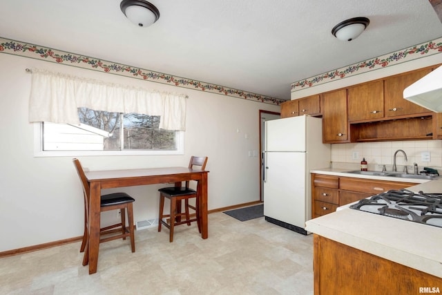 kitchen with sink, white fridge, range hood, and decorative backsplash