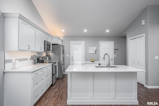 kitchen with white cabinets, stainless steel appliances, an island with sink, sink, and lofted ceiling