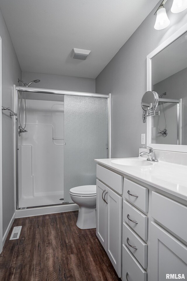 bathroom with toilet, vanity, hardwood / wood-style floors, and walk in shower