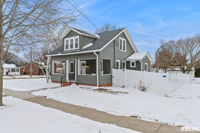 bungalow-style home with a porch, roof with shingles, and fence