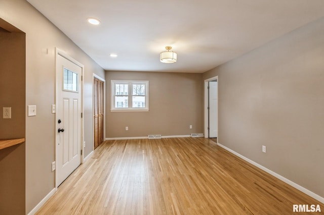 foyer entrance with light wood-type flooring, visible vents, and baseboards