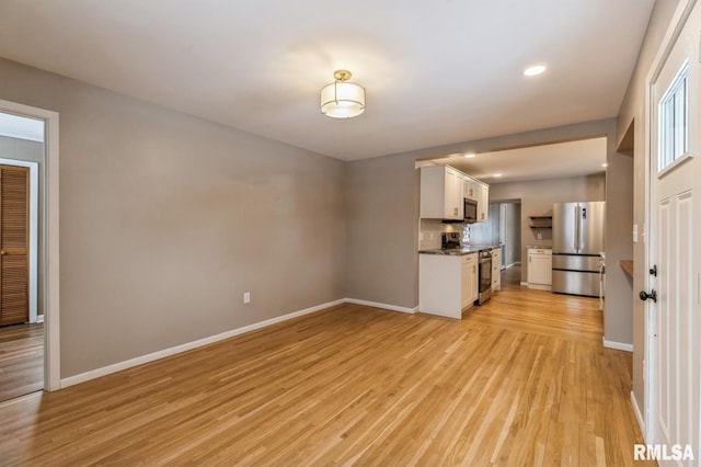 unfurnished living room with light wood-type flooring, baseboards, and recessed lighting