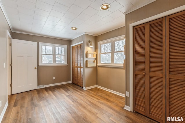 entryway featuring light wood-type flooring, visible vents, crown molding, and baseboards