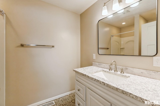 full bath featuring visible vents, baseboards, a shower, and vanity