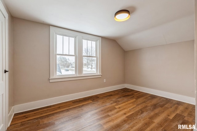 bonus room with dark wood-style floors, baseboards, and vaulted ceiling