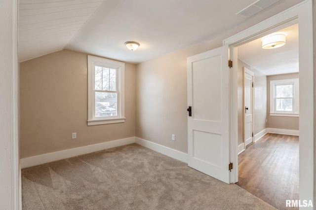 bonus room featuring lofted ceiling, visible vents, baseboards, and light colored carpet