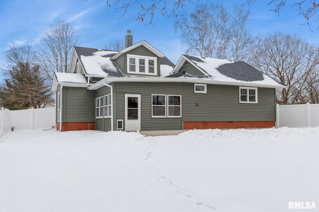 snow covered house with crawl space, a chimney, and fence