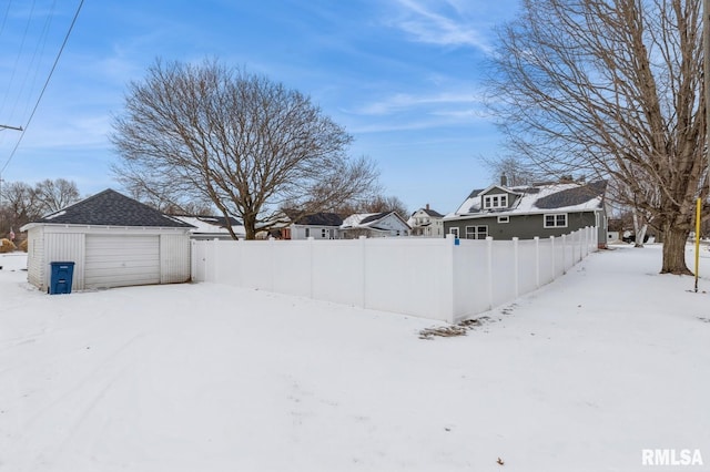 yard covered in snow with a garage, a residential view, and fence