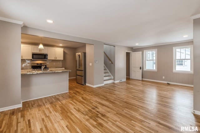 kitchen with white cabinets, appliances with stainless steel finishes, open floor plan, light stone counters, and pendant lighting