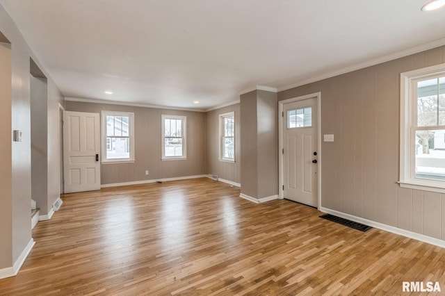 entryway with light wood-style floors, visible vents, and crown molding