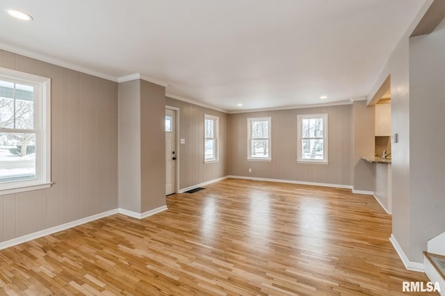 unfurnished living room featuring visible vents, baseboards, light wood-style flooring, and crown molding