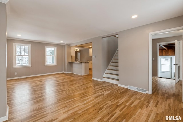 unfurnished living room with light wood finished floors, baseboards, visible vents, stairway, and recessed lighting