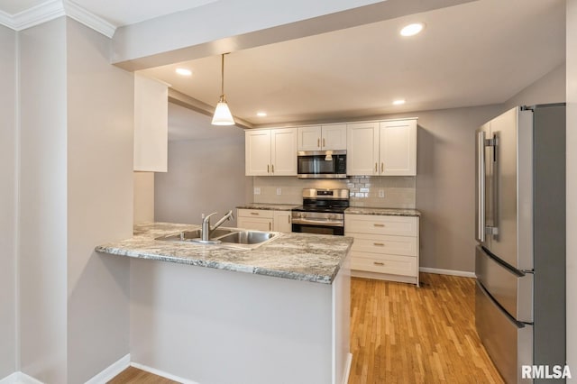 kitchen featuring decorative light fixtures, stainless steel appliances, white cabinetry, a sink, and a peninsula