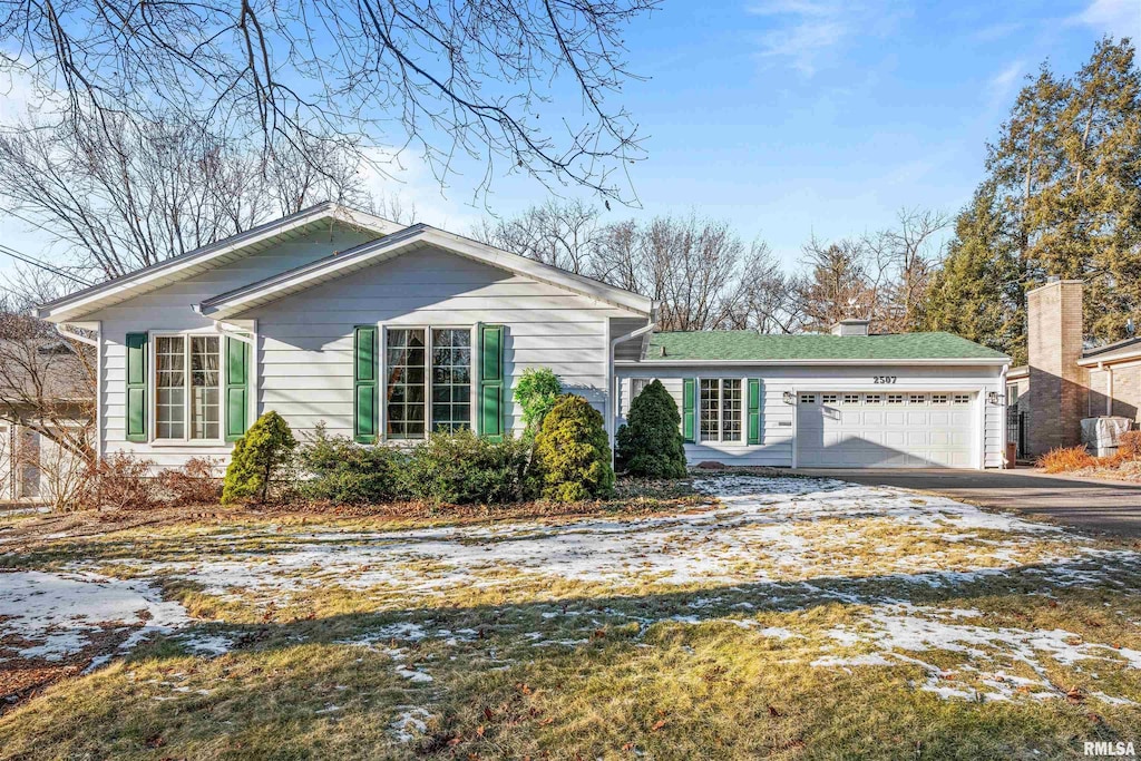 view of front of house with an attached garage, a chimney, and aphalt driveway