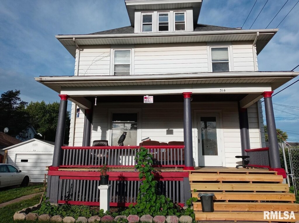 view of front facade with an outbuilding, covered porch, and a garage