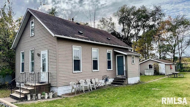 back of house with a lawn and a storage shed