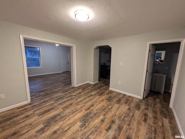 unfurnished room with a textured ceiling and dark wood-type flooring