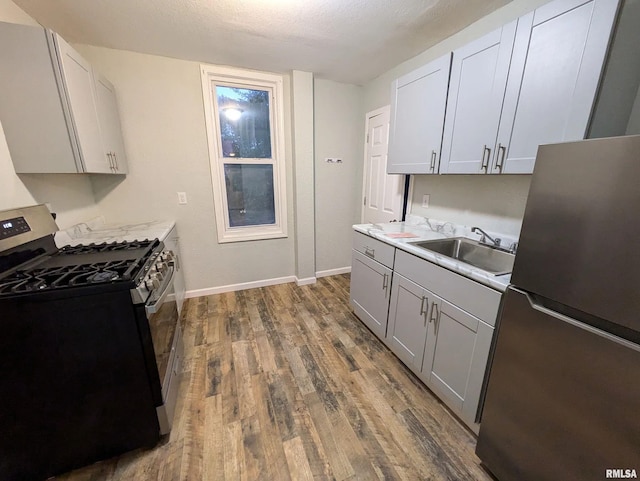 kitchen featuring a textured ceiling, appliances with stainless steel finishes, dark hardwood / wood-style flooring, and sink