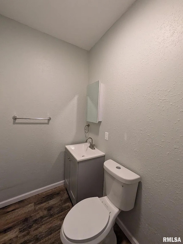 bathroom with toilet, vanity, and hardwood / wood-style flooring