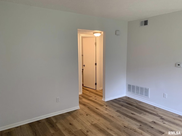 unfurnished room with a textured ceiling and light hardwood / wood-style flooring