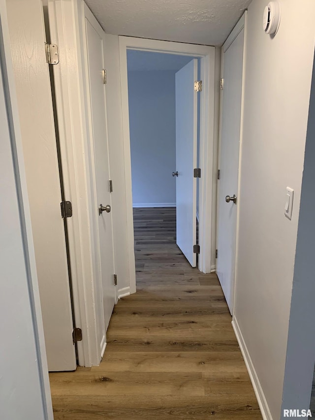 corridor with hardwood / wood-style floors and a textured ceiling