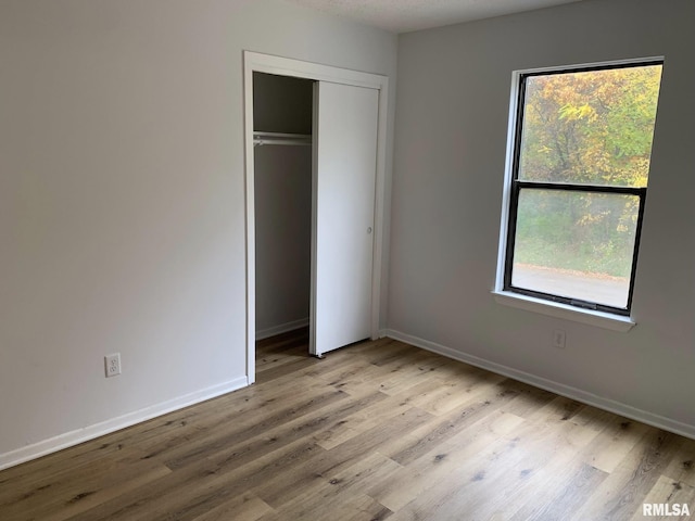 unfurnished bedroom featuring light wood-type flooring and a closet