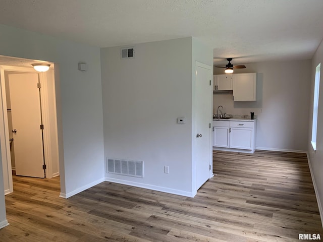 empty room featuring light wood-type flooring, ceiling fan, and sink