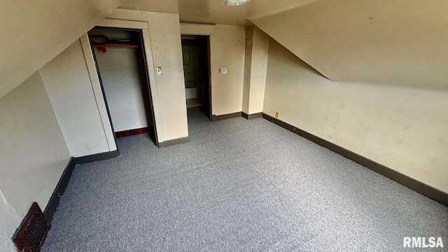 bonus room with dark carpet and vaulted ceiling