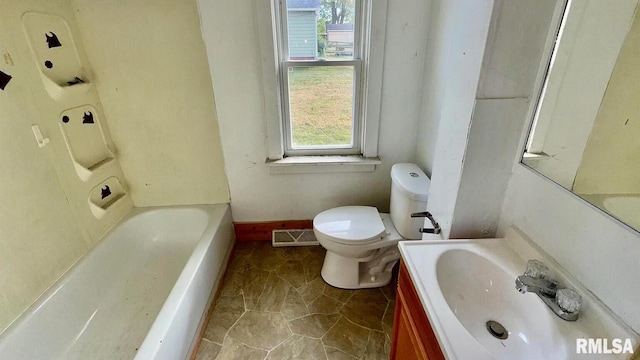 bathroom featuring a tub to relax in, a wealth of natural light, vanity, and toilet