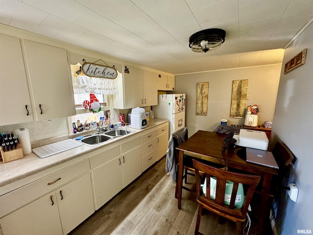 kitchen featuring sink, dark hardwood / wood-style flooring, white fridge, and white cabinets