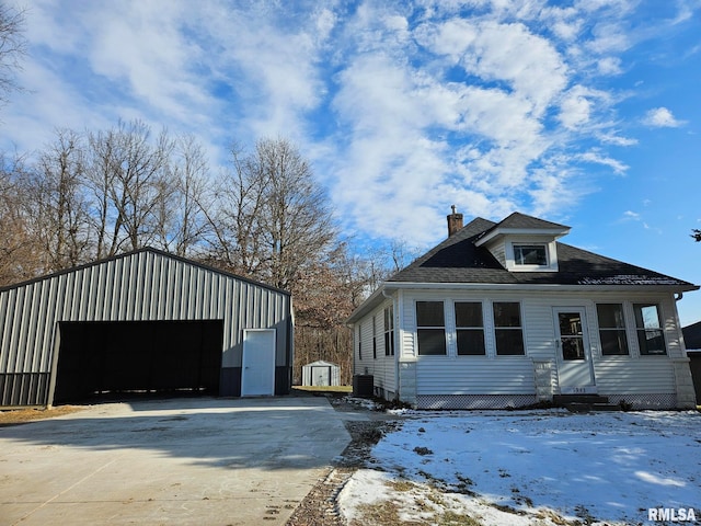 view of front of home featuring a garage, an outdoor structure, and central AC