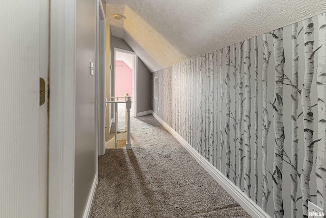 hall featuring vaulted ceiling, a textured ceiling, and carpet floors