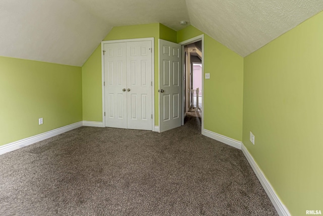 additional living space featuring lofted ceiling, dark carpet, and a textured ceiling