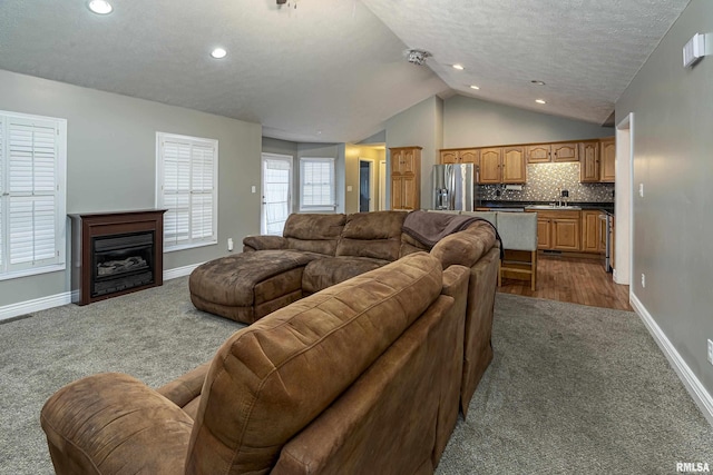 carpeted living room featuring sink, a textured ceiling, and lofted ceiling