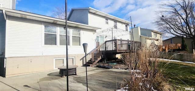 back of house with a wooden deck and a patio