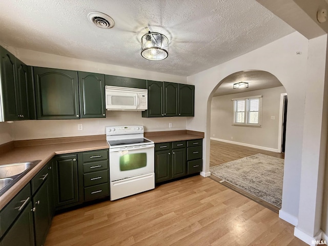 kitchen with white appliances, green cabinets, a textured ceiling, and light wood-type flooring