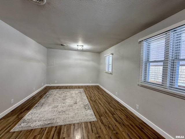 spare room with dark hardwood / wood-style flooring, a wealth of natural light, and a textured ceiling