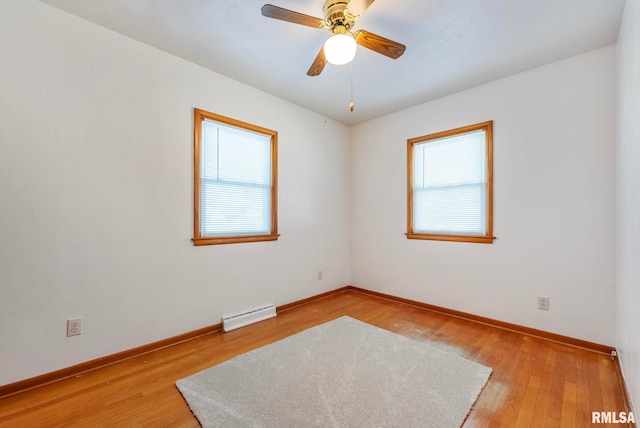 empty room featuring ceiling fan, baseboard heating, plenty of natural light, and light hardwood / wood-style floors