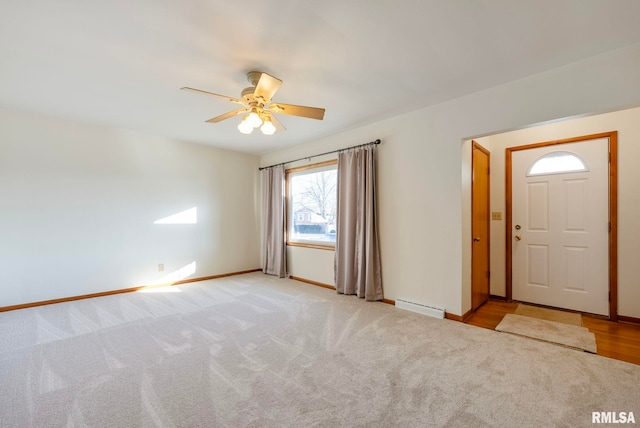 foyer entrance featuring ceiling fan, light colored carpet, and a baseboard heating unit