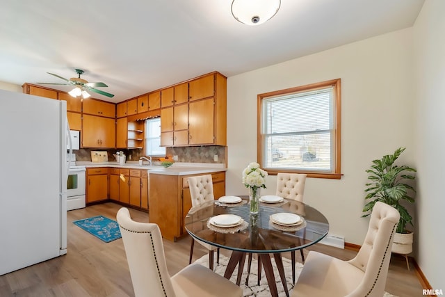 kitchen featuring white appliances, decorative backsplash, sink, ceiling fan, and light hardwood / wood-style flooring