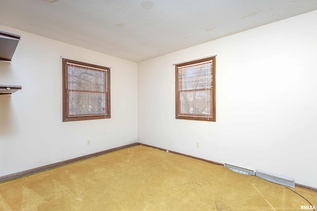 carpeted empty room with a textured ceiling