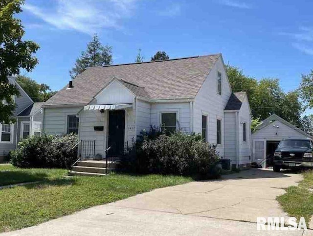 bungalow featuring a garage, a front lawn, and an outdoor structure