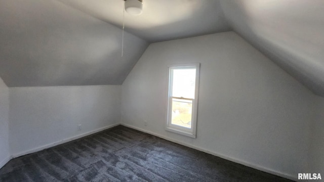 bonus room with lofted ceiling and dark colored carpet