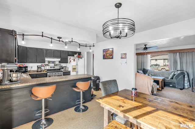 kitchen featuring ceiling fan with notable chandelier, white refrigerator with ice dispenser, hanging light fixtures, kitchen peninsula, and gas range